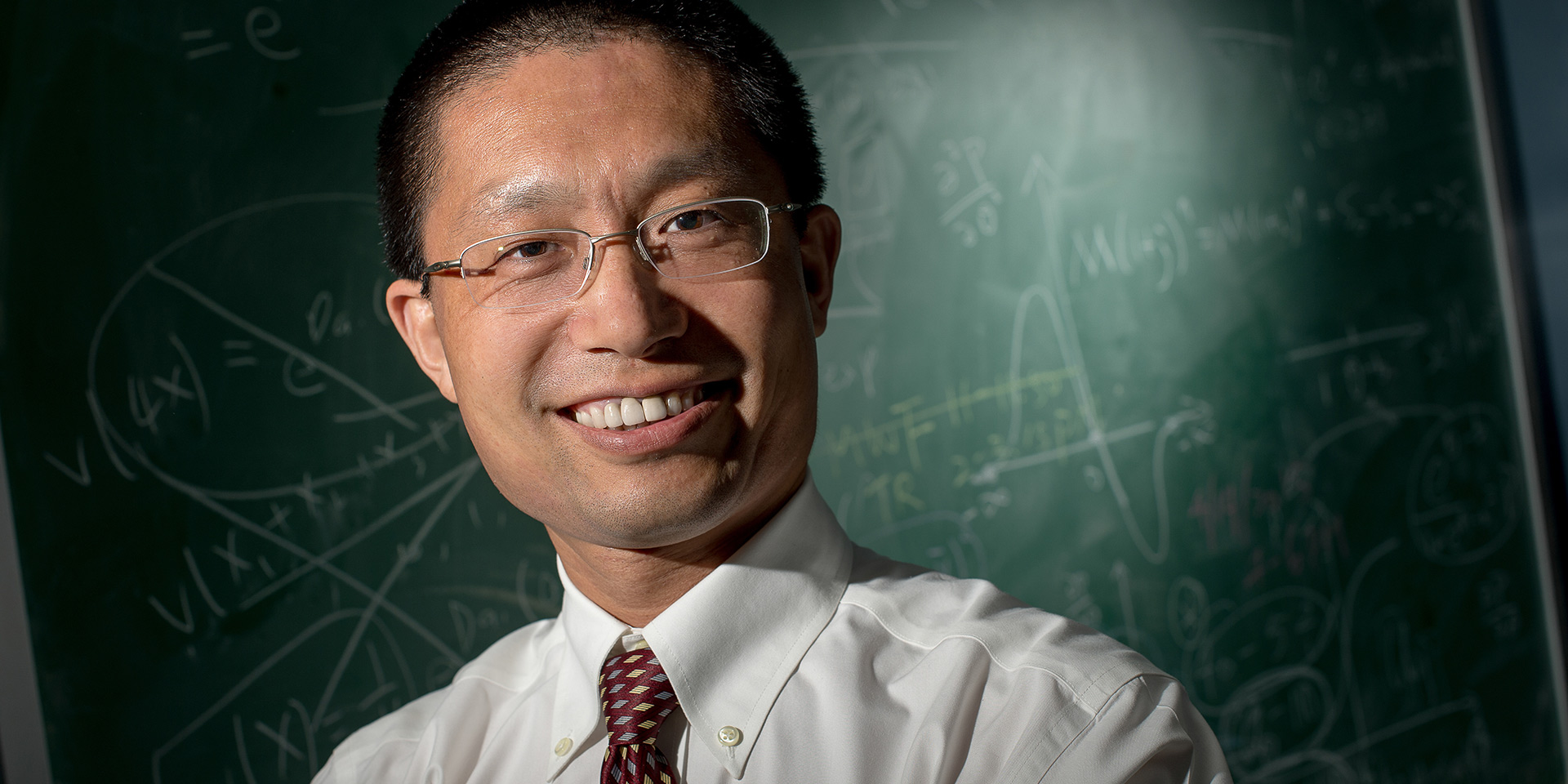 Math professor standing in front of chalkboard with equations