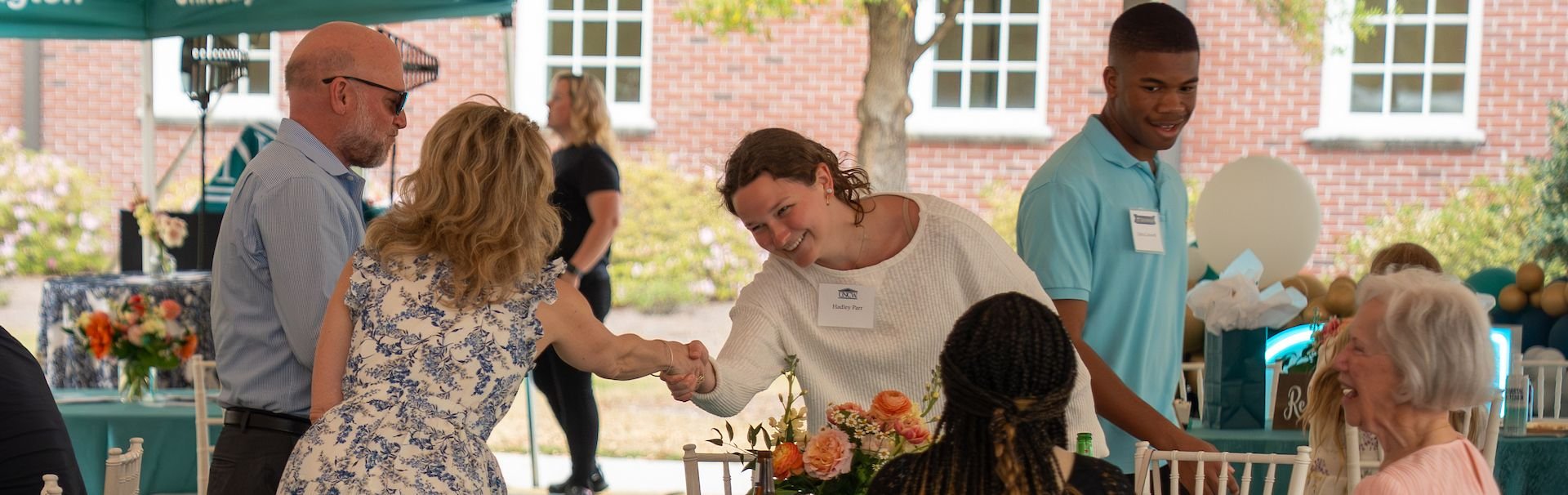 Community partners and donors shake hands while attending an on campus celebration. 